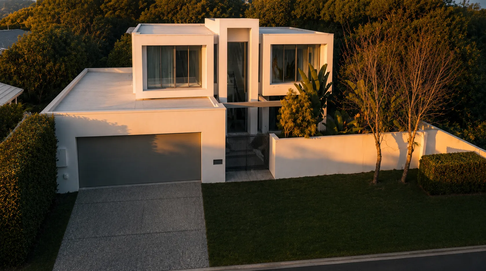 Golden-hour front elevation of The Bundall House with grey garage door and landscaped lawn