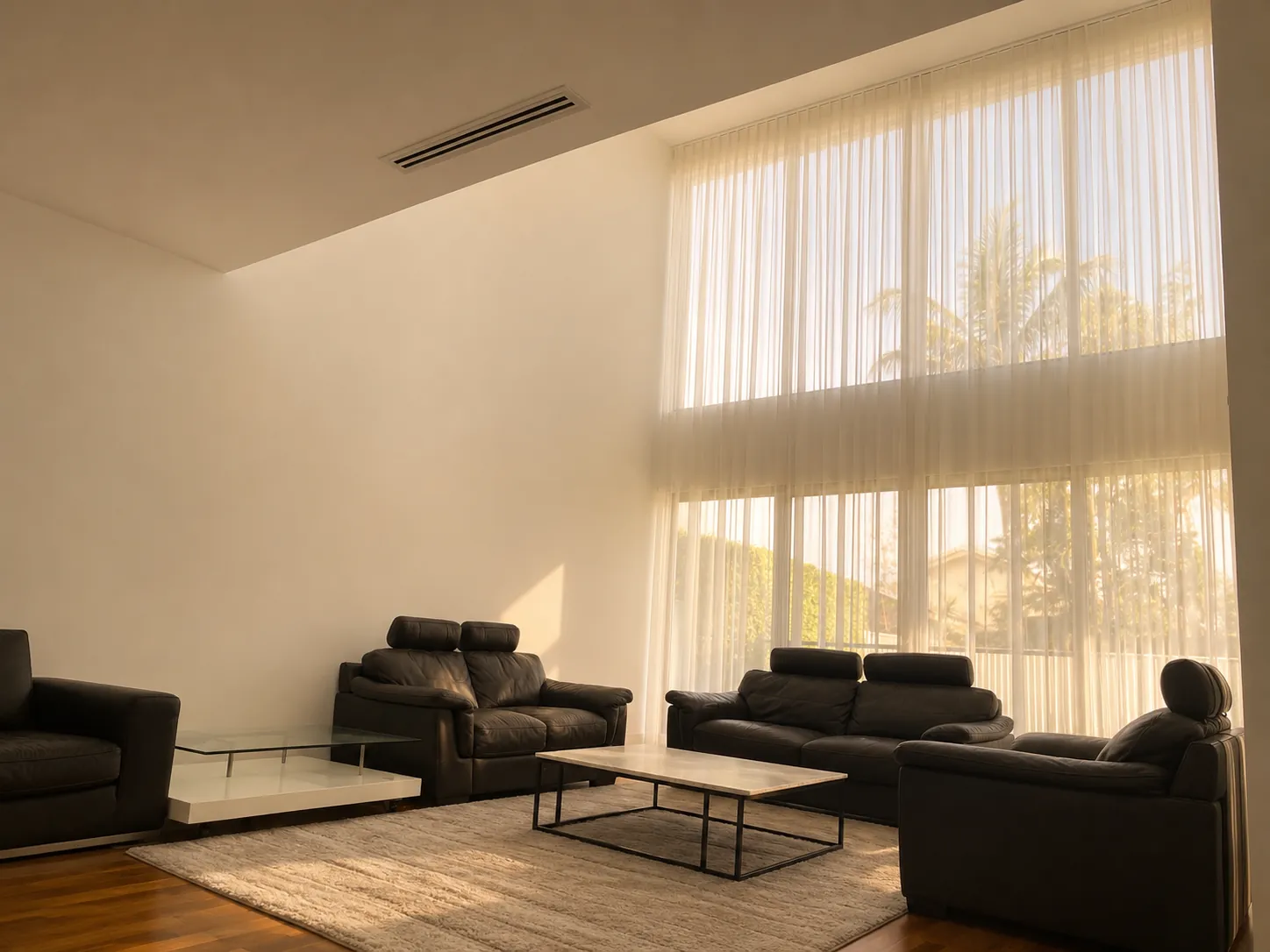 High-ceiling living room with full-height sheer curtains and leather lounges
