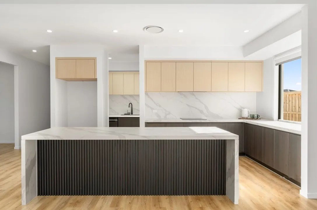 Kitchen with marble-look island, fluted dark cabinetry and pale timber overheads