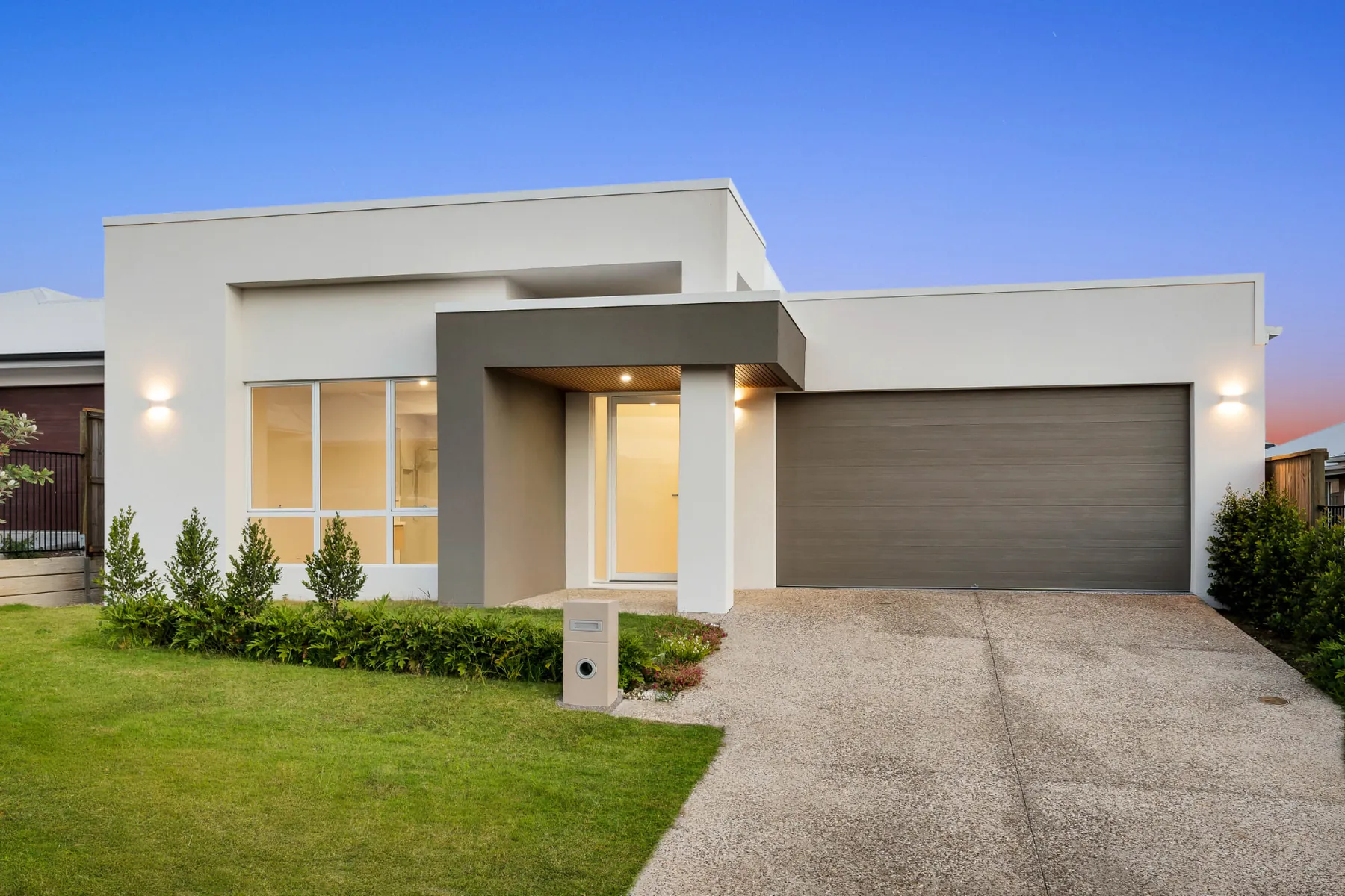 Twilight street elevation of The Stuart Home with warm entry and exterior lighting