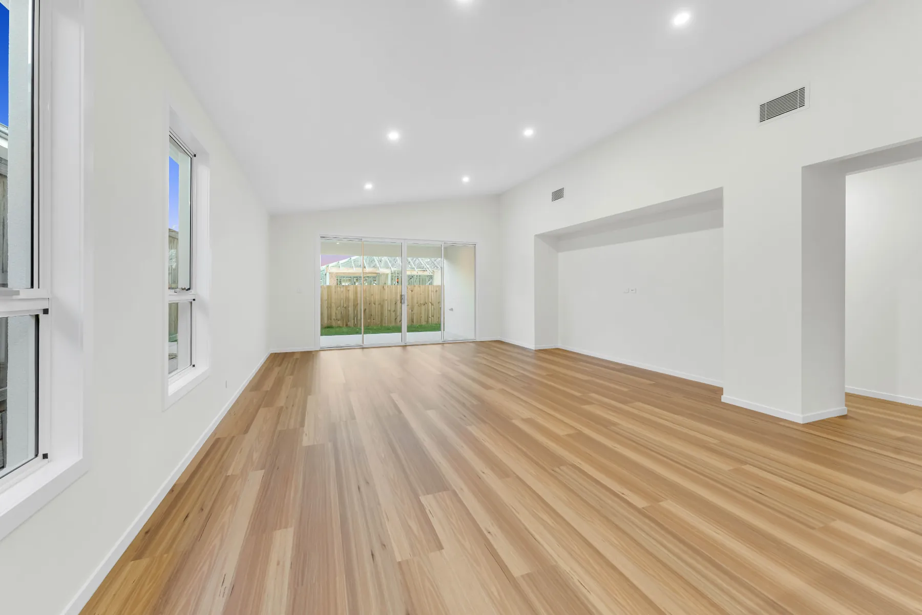 Open living space with timber floors and sliding glass doors to the rear yard